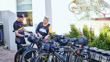 A group of bicycles parked outdoors, possibly in a residential area with a white building in the background.