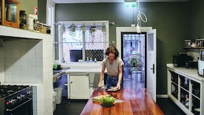 A kitchen with a wooden table, white cabinets, and a window with a view. - Black Diamond Lodge (Collie)