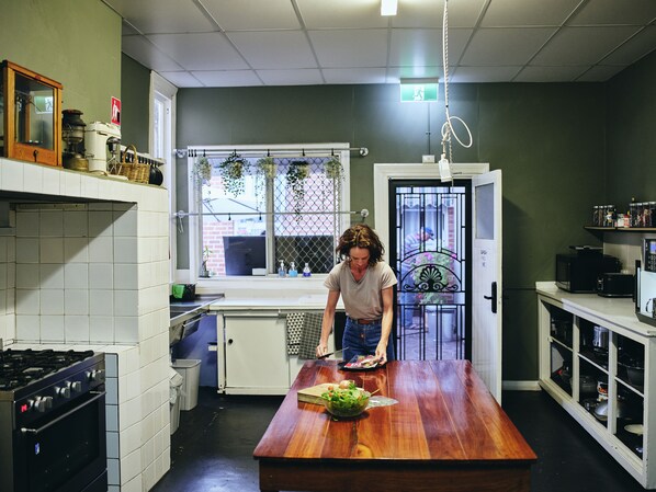 A kitchen with a wooden table, white cabinets, and a window with a view.