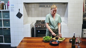 A kitchen with a stove, a bowl of salad, a cutting board with vegetables, and a wine bottle. - Black Diamond Lodge (Collie)