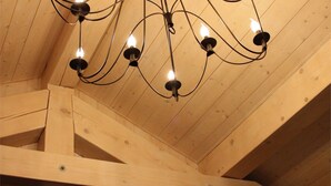 A wooden ceiling with exposed beams and a modern chandelier with multiple bulbs. - <<<<>>>> (Les Gets)