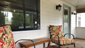 Une véranda avec deux chaises, une petite table et une fenêtre donnant sur les arbres.