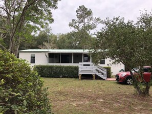 A single-story house with a covered porch and a small staircase leading to the entrance. - Peaceful forest cottage meticulously updated for your comfort. (Ocklawaha)
