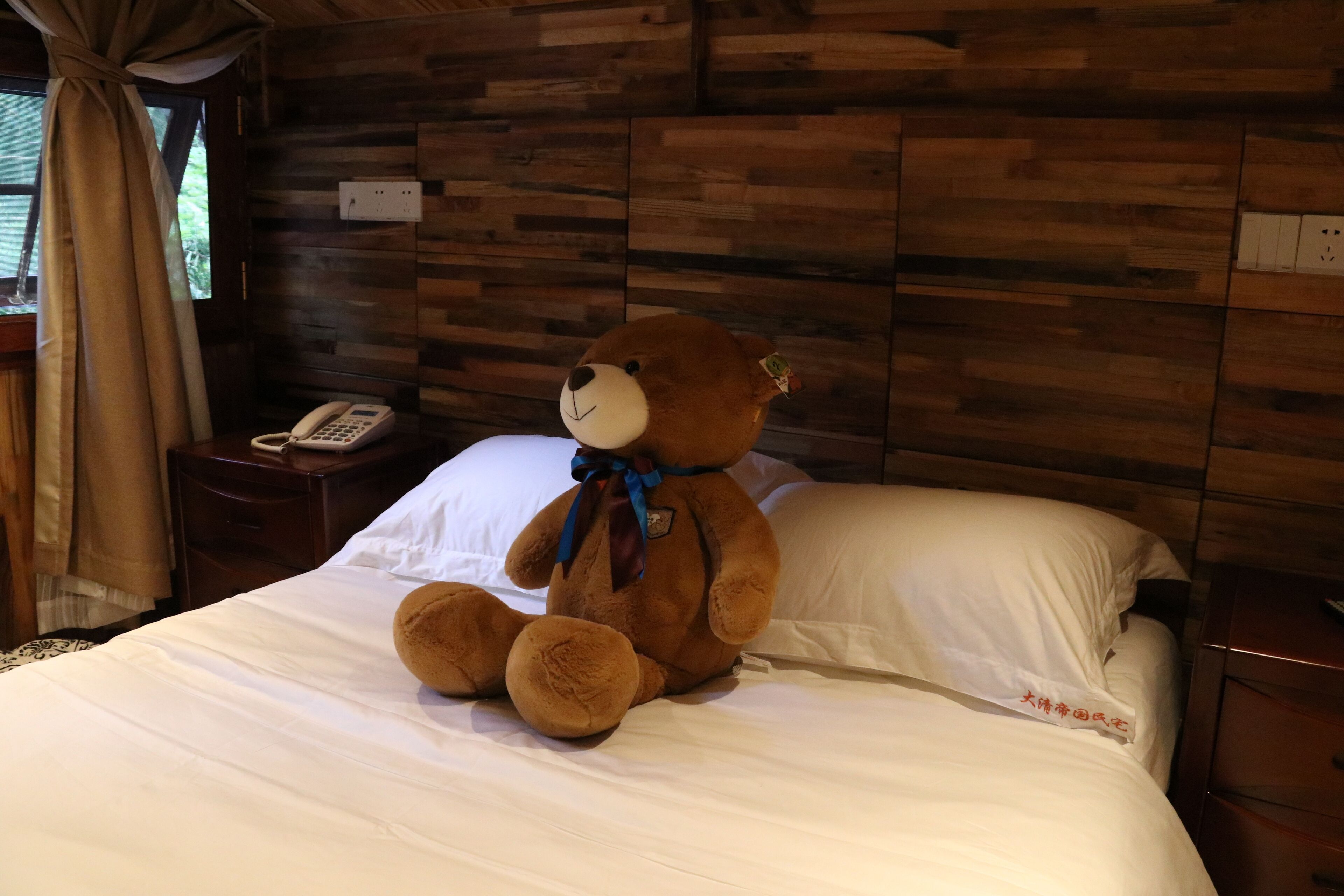 Ein Bett mit Teddybär, Nachttischtelefon und Holzvertäfelung.
