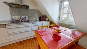 Een keuken met witte kastjes, een granieten aanrecht en een eettafel met rode placemats.