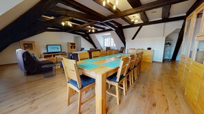 A spacious loft with a high ceiling, exposed wooden beams, a long dining table, and a television in the background. - le saphir 1 free parking city center 3br 2bt (Colmar)