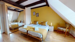 Een slaapkamer met twee bedden, een spiegel, een stoel en een nachtkastje.