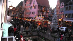 Een traditioneel Europees stadsplein met historische gebouwen, een markt en een kerstboom.