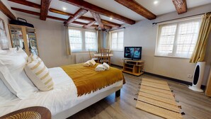 Een slaapkamer met een bed, een televisie, een spiegel en een raam.