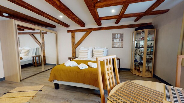 Een slaapkamer met een bed, een houten stoel, een kleine tafel, een kledingkast en een spiegel.