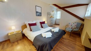 Une chambre à coucher comprenant un lit, une table de chevet, une chaise et donnant sur un couloir.