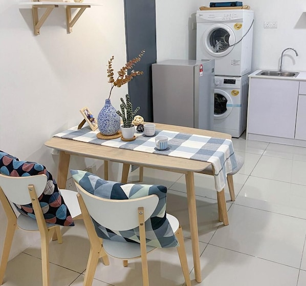Cocina y comedor con una mesa, sillas, lavadora y fregadero.