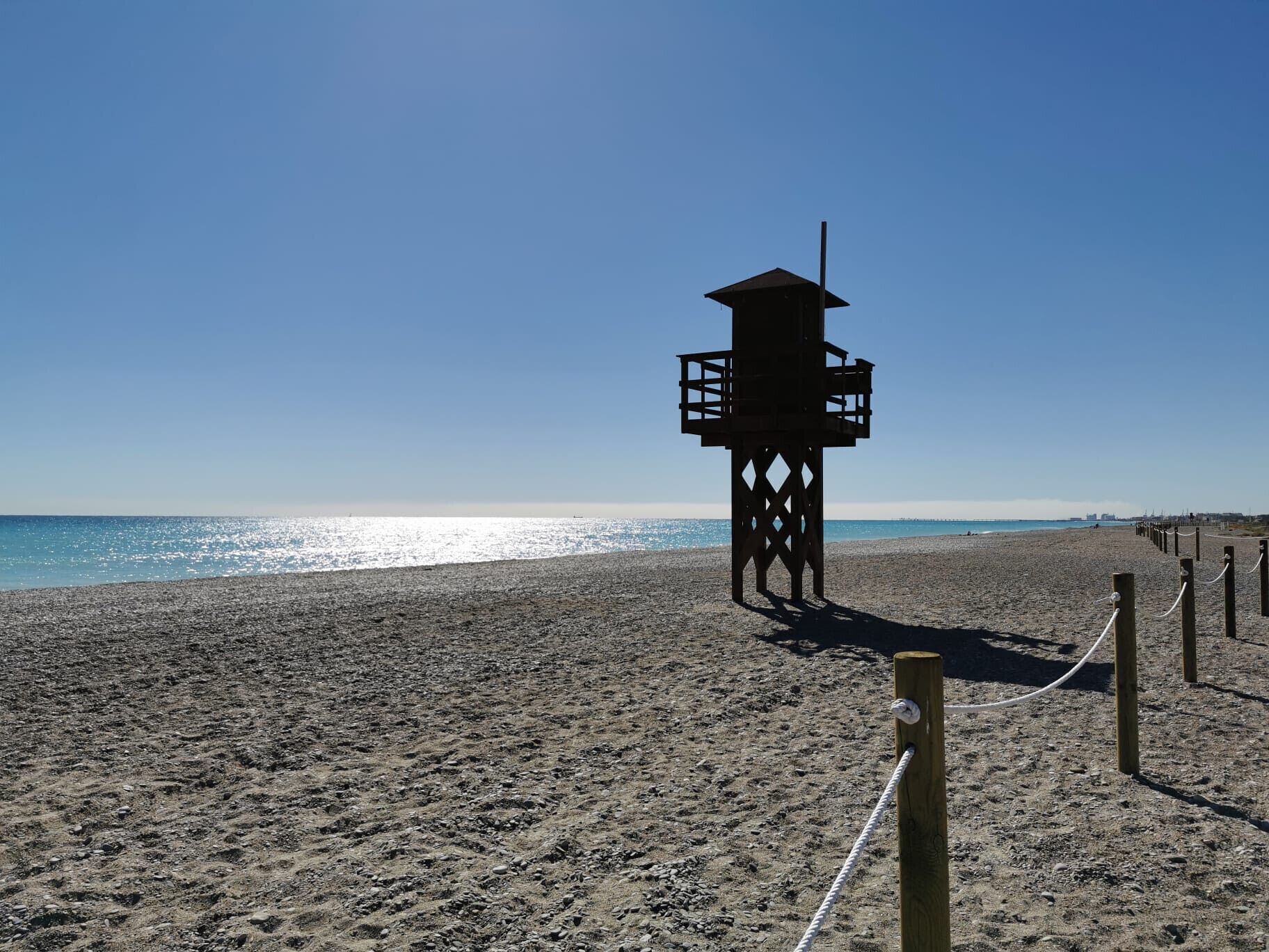 A lifeguard tower on a beach with a clear sky.