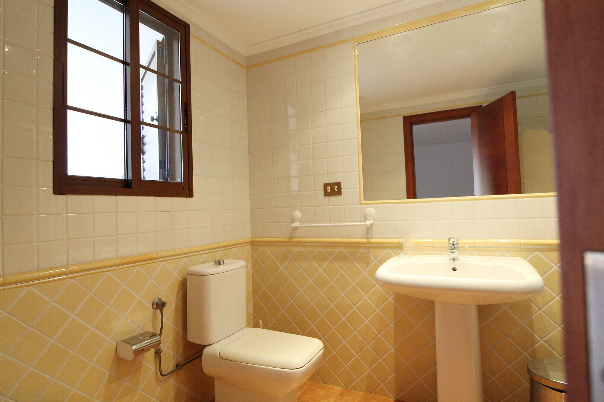 A bathroom with a toilet, sink, and window.