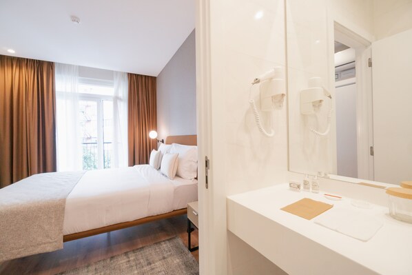 Een hotelkamer met een bed, een badkamer met spiegel en een haardroger.