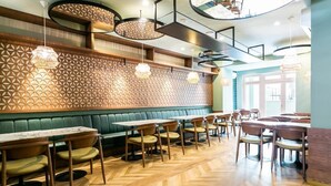 A restaurant with wooden herringbone flooring, green cushioned booths, and pendant lighting. - Lx SoHo Boutique Hotel by RIDAN Hotels (Lisbon)