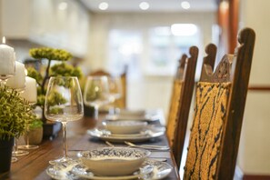 A dining table set with plates, glasses, and candles, with chairs featuring a unique design. - Greenwich Manor Gorgeous Hideout in Central Location (Sidcup)