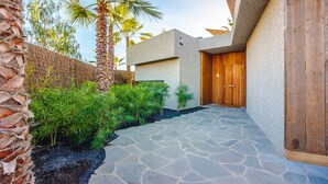 Une maison moderne avec un chemin de pierre menant à une porte en bois.