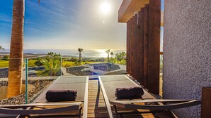 Un espace de détente extérieur, baigné de soleil, avec deux fauteuils inclinables, une petite piscine et une vue sur l’océan.