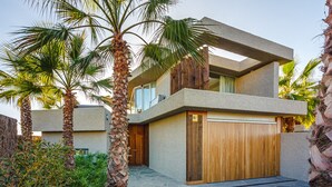 Un bâtiment moderne à deux étages, doté d’une façade en pierre, d’une porte de garage en bois et d’un balcon.