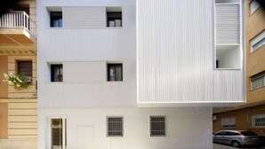 A modern multi-story building with a flat facade, multiple windows, and a visible entrance. - IBERICABEDS CENTER 1 BEDROOM (Granada)