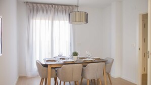 Een eetkamer met een houten tafel gedekt voor vier personen, omringd door vier stoelen.