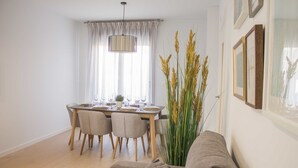 Een eetgedeelte met een tafel voor vier personen, een bank en hoge planten.