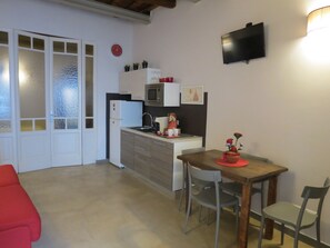 A compact kitchen with a microwave, refrigerator, and a small dining area with a wooden table and chairs.
