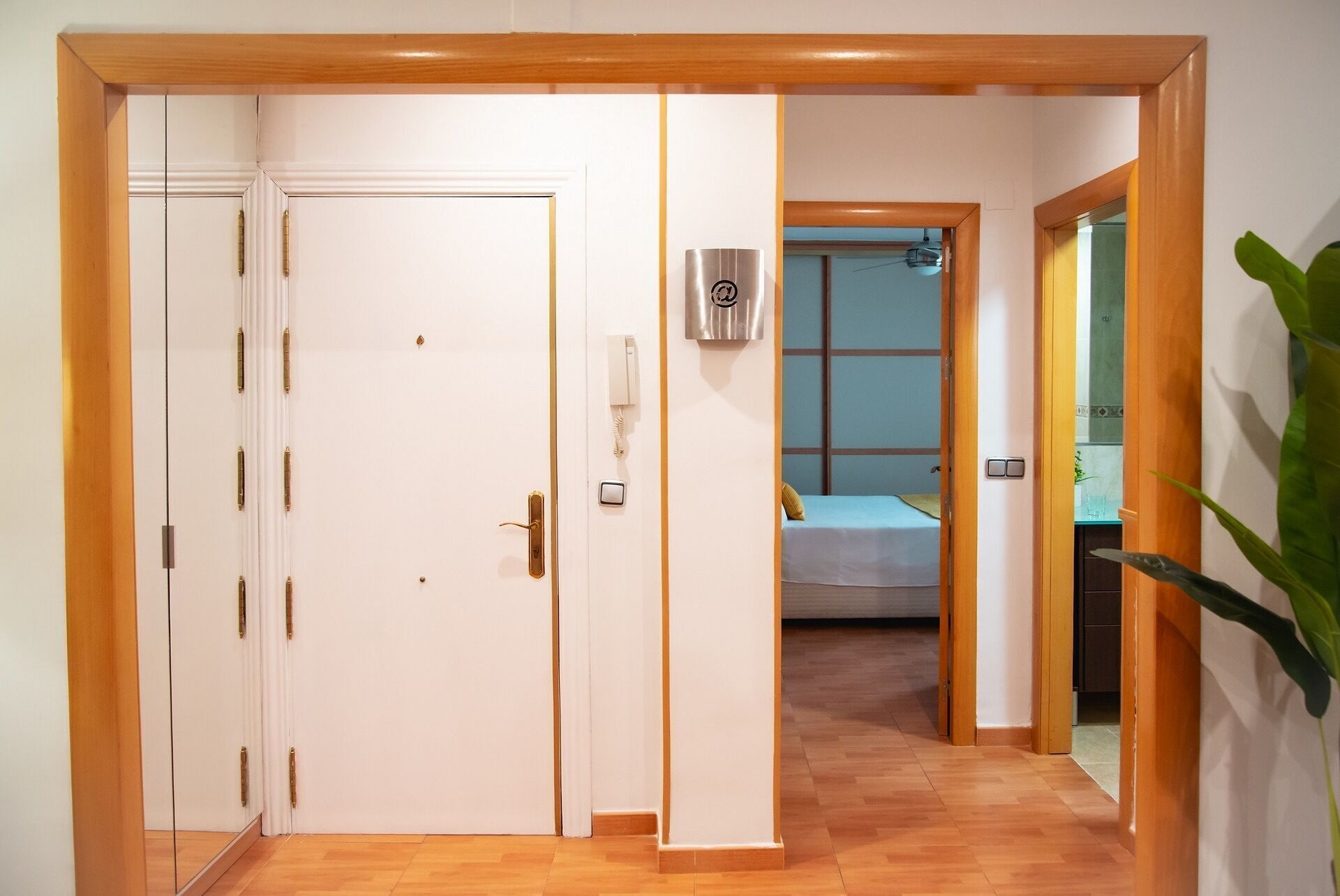 Una habitación de hotel con suelo de madera, una cama con colcha azul, una mesita de noche y un espejo.