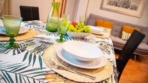Taula de dinar coberta amb plats, cuissos i coberts, envoltada de sovintalls teixits i vidre verd.