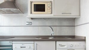 Una cuina compacta amb microones, rentaplats i rentadora.