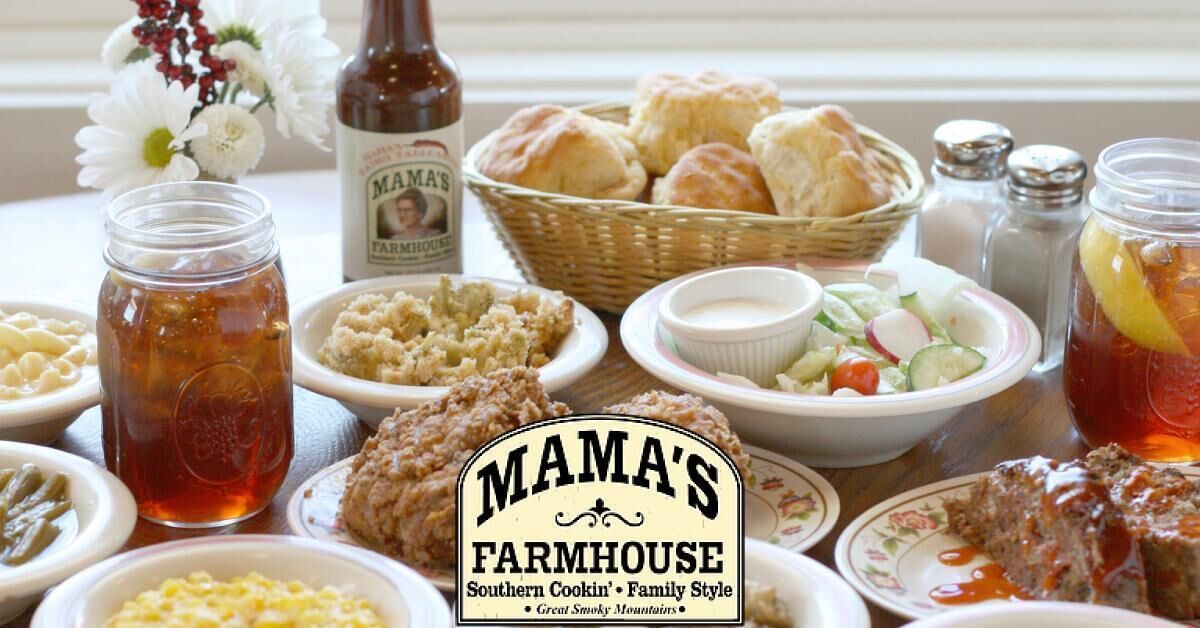 A table with various dishes, including biscuits, salad, and a jar of pickles.