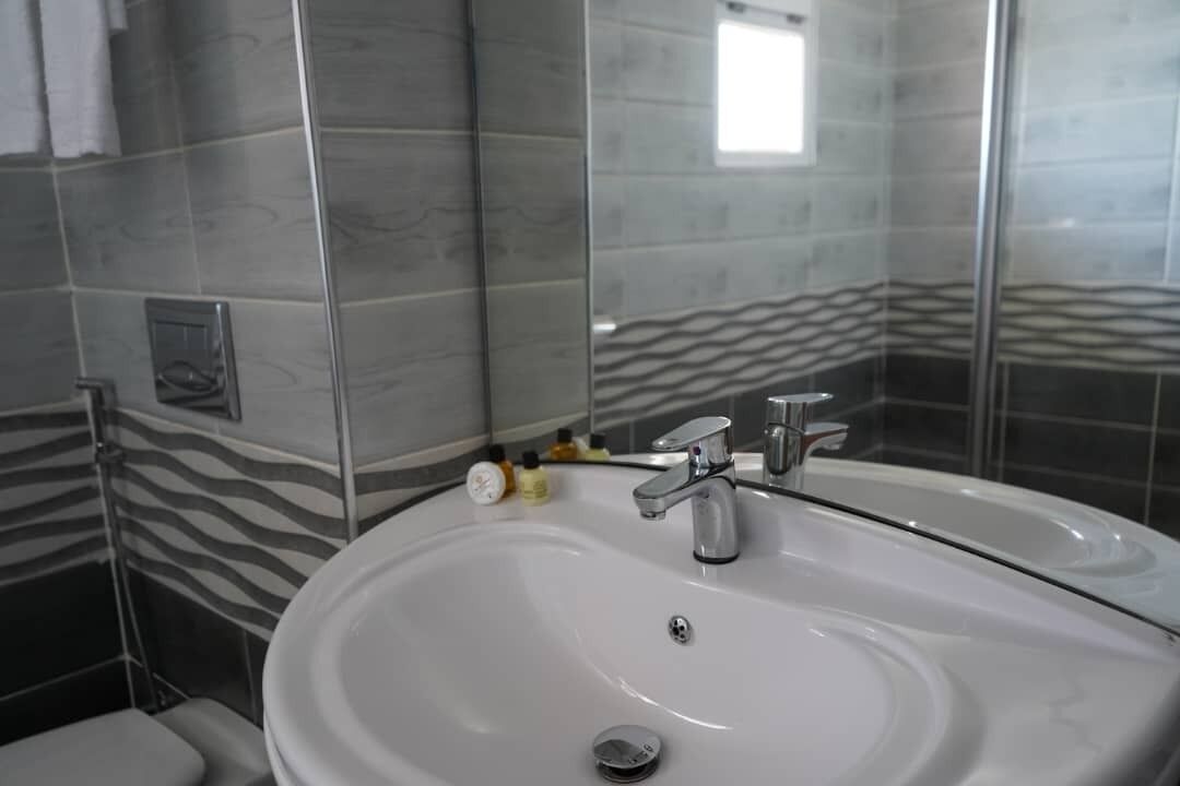 Un baño con un lavabo blanco, un espejo y una pared con estampado de cebra.