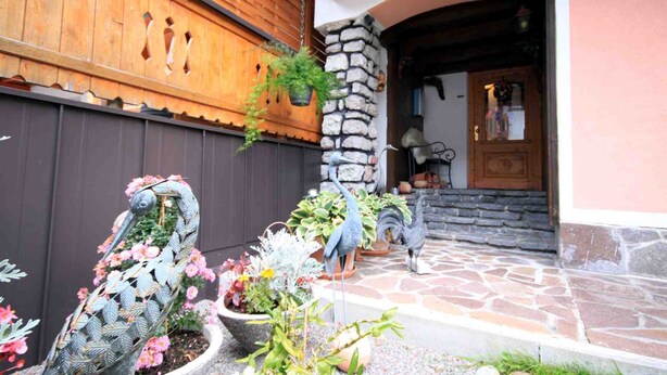 A building with a wooden facade, stone pillar, and a stone-tiled entrance. - Haus Hrabovsky (Laengenfeld)