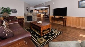A living room with a leather sofa, a coffee table, a fireplace, and a television. - 3204 Golf View Hillcrest Mountain Sanctuary (Pigeon Forge)