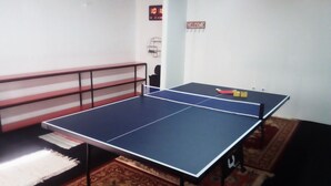 Ein Zimmer mit Tischtennisplatte, einer Couch und einer Wanduhr.