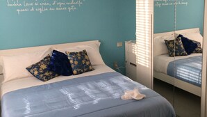 Ein Schlafzimmer mit einem Bett, Kissen, einem Nachttisch, einem Spiegel und einer Wand mit Schrift.