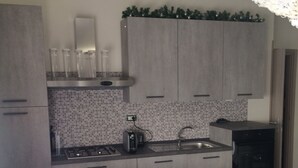 Eine moderne Küche mit grauen Schränken, einer gefliesten Spritzschutzwand und einem Esstisch, gedeckt mit einer Tischdecke mit Herzmuster.