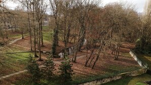 A park with a stone wall, trees, and a grassy area.