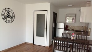 A compact living space with a dining area, a kitchen with a refrigerator and microwave, and a door with a frosted glass panel.