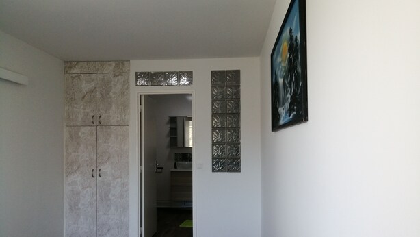 A hallway with a marble cabinet, a door leading to a bathroom, and a framed picture on the wall.