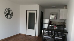 A compact living space with a kitchenette, a dining area, and a sofa with a blanket.