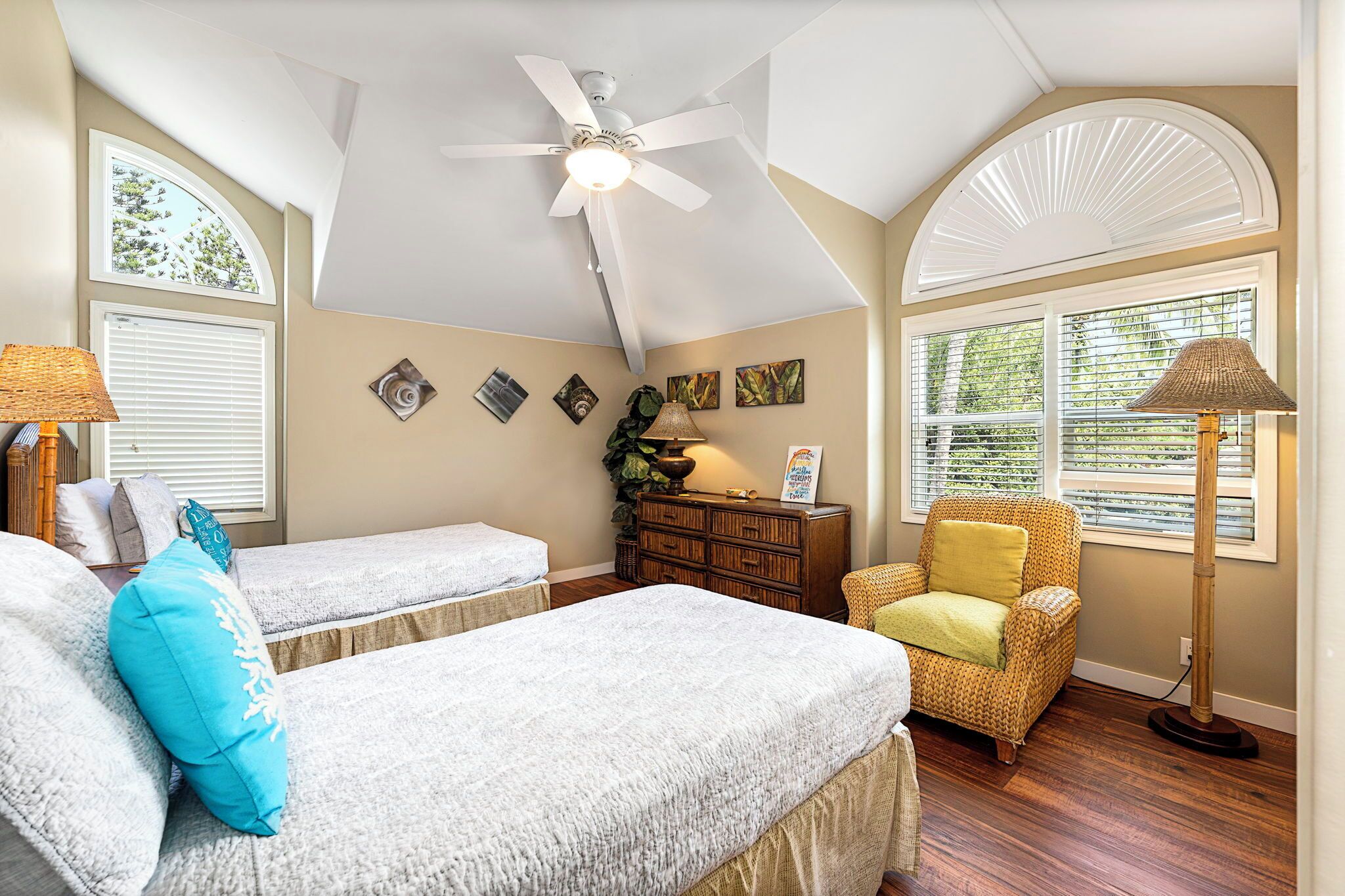 A bedroom with two beds, a ceiling fan, a window with blinds, a chair, and a floor lamp.