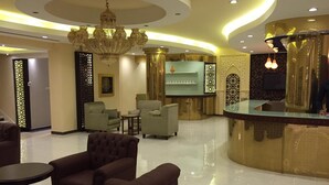 A lobby with a reception desk, seating area, and decorative elements like a chandelier and patterned walls. - ashbona hotel suites (Riyadh)