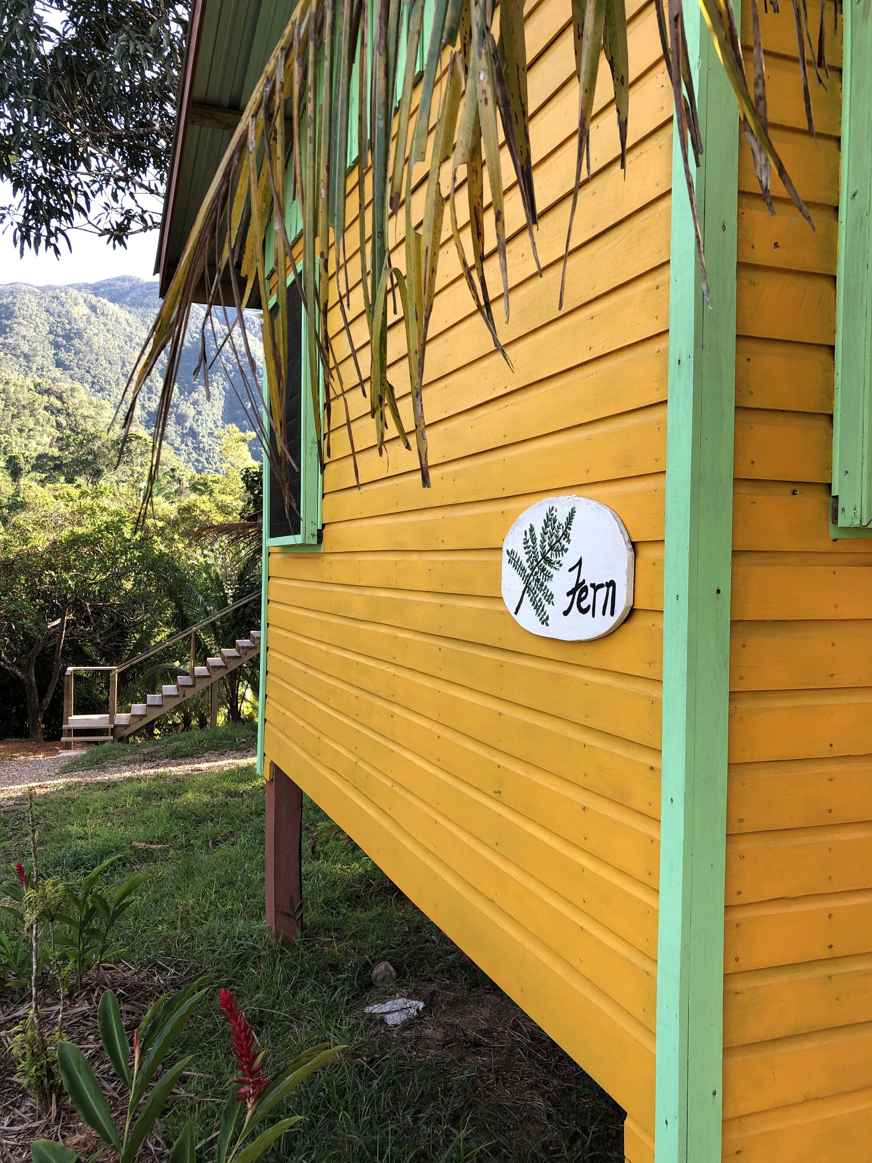 A yellow building with a green roof and a sign with Japanese characters.