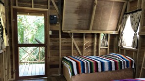 A rustic wooden room with a bed, a window, and a door. - T.R.E.E.S Research Center and Eco Lodge (Belmopan)
