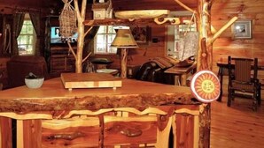 A rustic cabin interior with a wooden bar, a television, and a large window. - Enchanted - 1 Bedrooms, 1 Baths, Sleeps 2 Cabin by RedAwning (Newport)