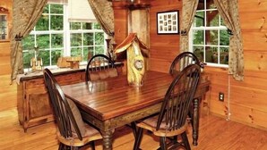 A wooden dining table with four chairs, a wooden cabinet, and a window with curtains. - Enchanted - 1 Bedrooms, 1 Baths, Sleeps 2 Cabin by RedAwning (Newport)