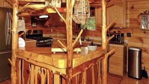 A rustic kitchen with wooden cabinetry, a stainless steel refrigerator, a stove, and a trash can. - Enchanted - 1 Bedrooms, 1 Baths, Sleeps 2 Cabin by RedAwning (Newport)