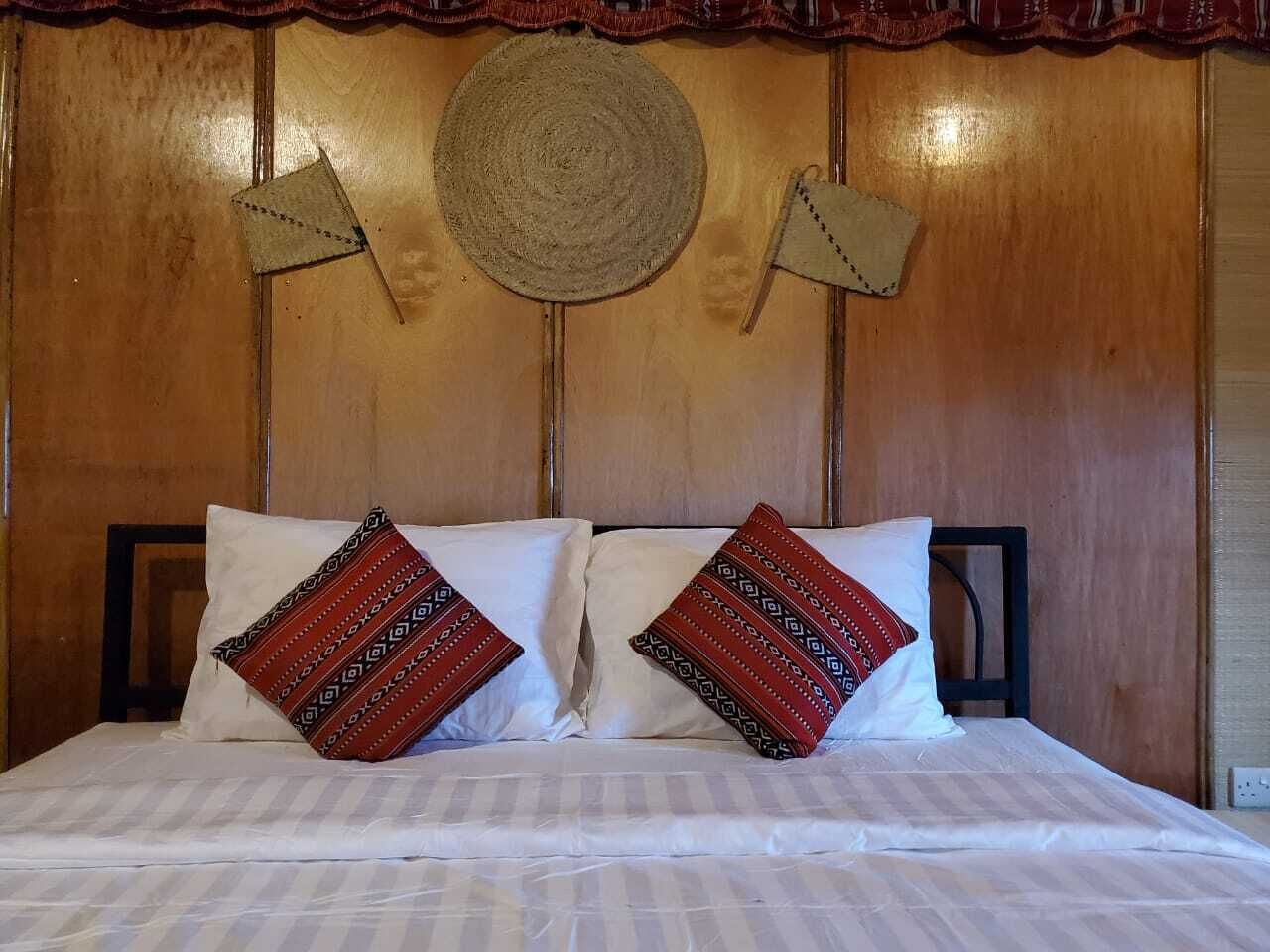 Una cama con sábanas blancas y dos almohadones decorativos con diseños geométricos.